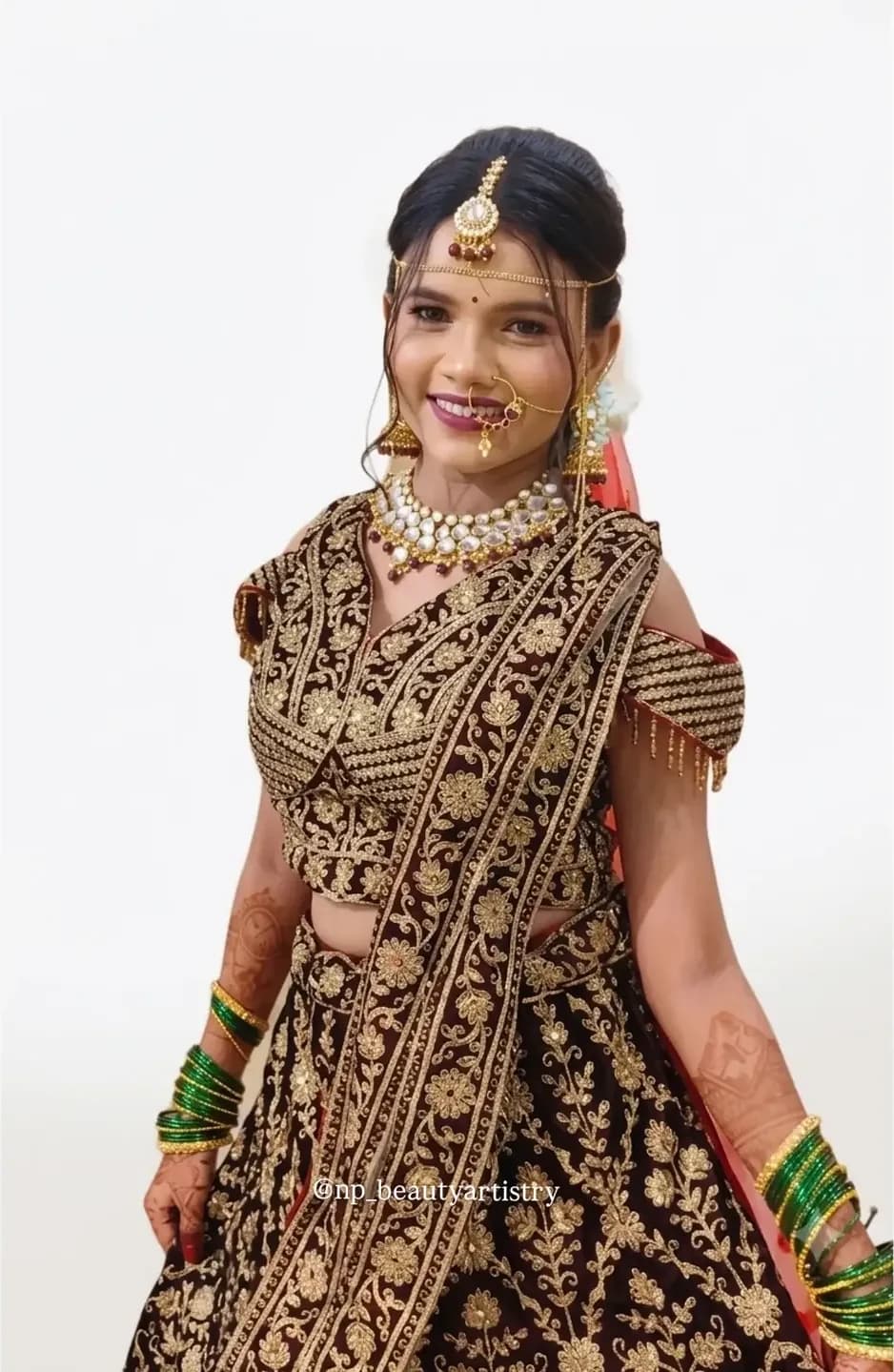 Bride in a maroon and gold velvet lehenga with kundan jewellery, maang tikka and a soft matte base