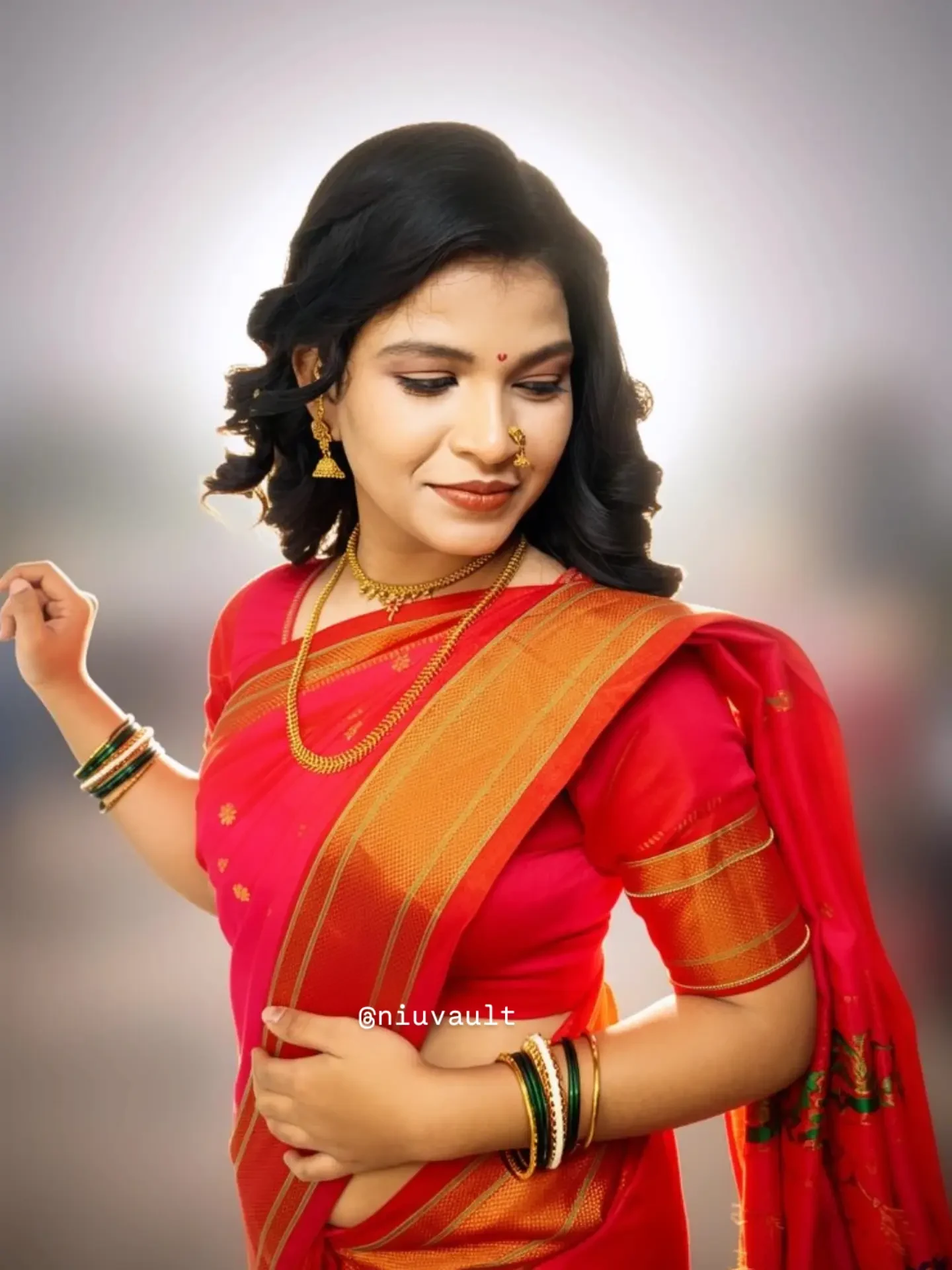 Traditional red silk saree look with a nath, gold jewellery and soft brushed-out curls